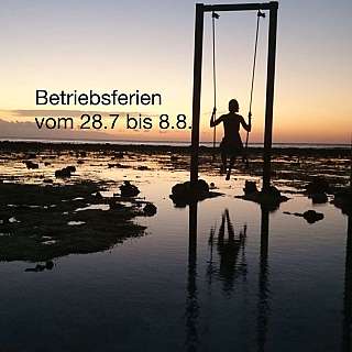 Eine Person schwingt auf einer Schaukel am Strand bei Sonnenuntergang.
