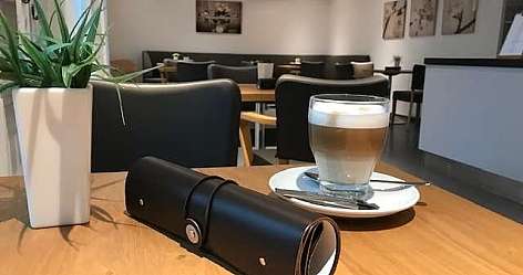 Ein Glas Latte Macchiato auf einem Holztisch in einem Café.