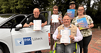 Menschen mit ihren Zertifikaten vor einem Auto 
